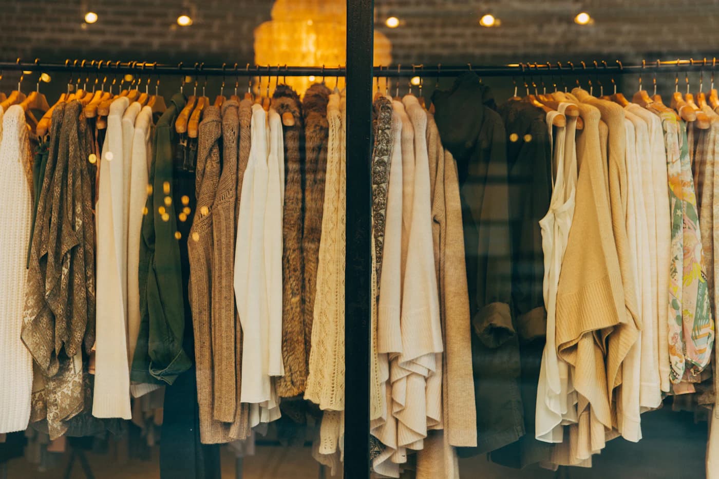 Rack of warm-toned knitwear and coats in a shop window