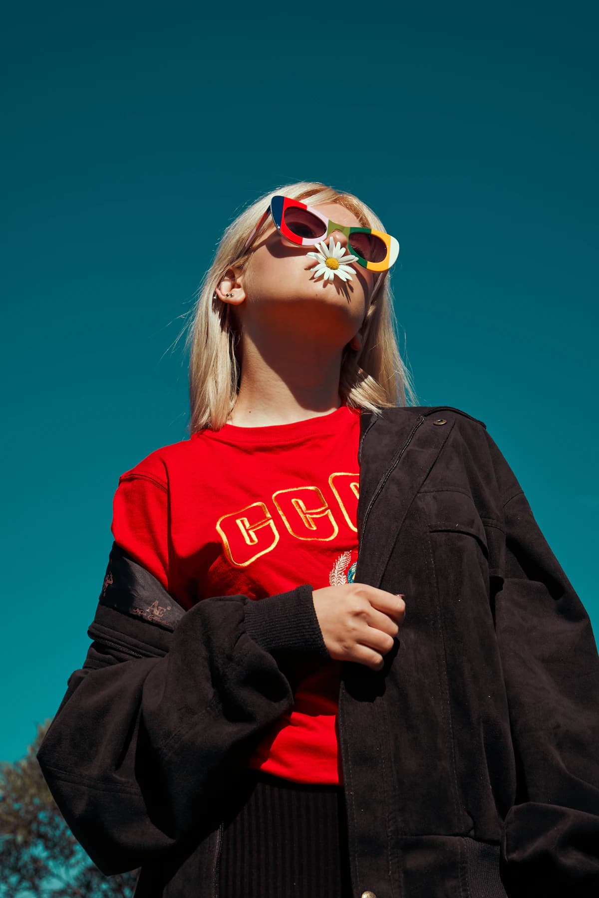 Person in sunglasses wearing a red tee and black jacket